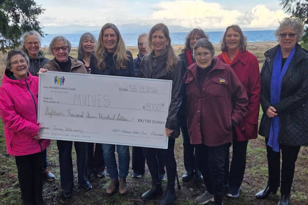 Mid Vancouver Island Habitat Enhancement Society president Barb Riordan and secretary Shelley Goertzen hold a donation from the 100 Women Who Care Oceanside, along with nominator Lisa Stockwood. Also in the photos are members of MVIHES and 100 Women group. (Contributed photo)